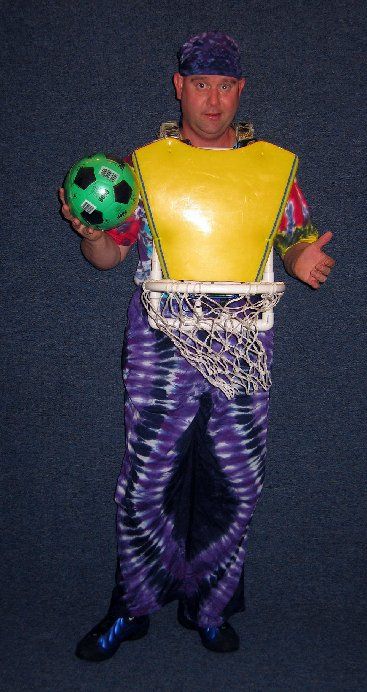 A man in a yellow vest is holding a green soccer ball
