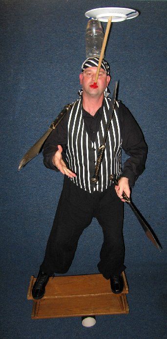 A man is juggling a bottle and a plate on his head.