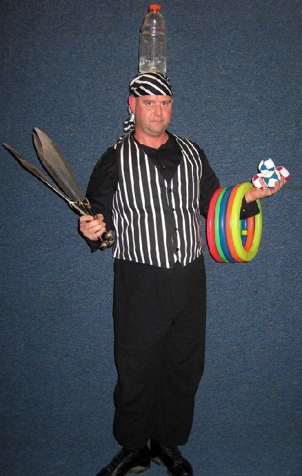 A man in a pirate costume is holding balloons and a bottle on his head