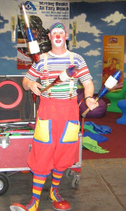 A man dressed as a clown is juggling clubs
