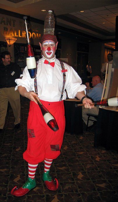A man dressed as a clown juggling bottles on his head