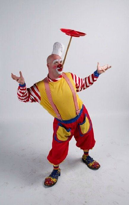 A clown is juggling a plate on a stick