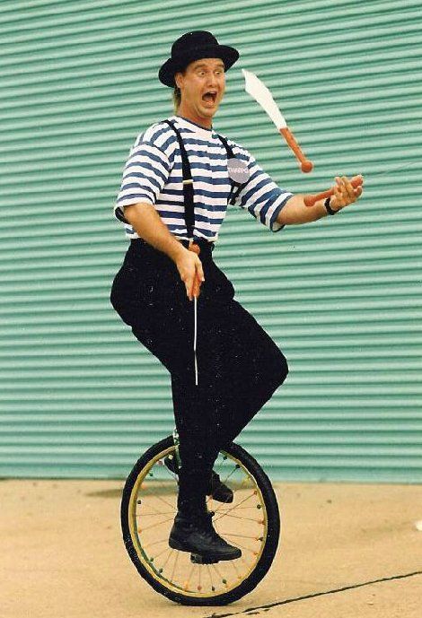 A man in a striped shirt is riding a unicycle