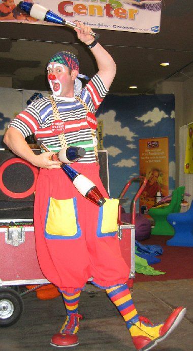 A clown holding a juggling stick in front of a sign that says center