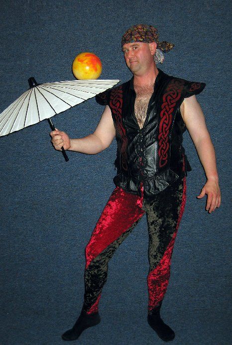 A man balances a ball on his head while holding an umbrella