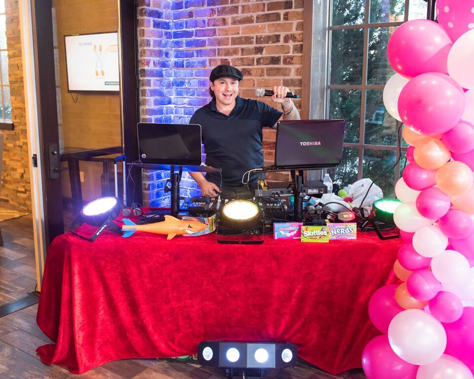 A man is standing behind a table with balloons and a laptop on it.