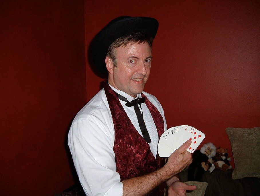 A man in a hat and vest is holding a deck of playing cards