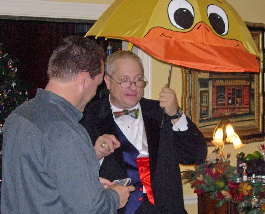A man in a tuxedo is holding an umbrella with a duck face on it