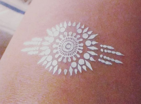 A close up of a white tattoo on a person 's arm.