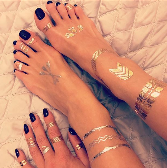 A close up of a woman 's feet and hands with rings and bracelets