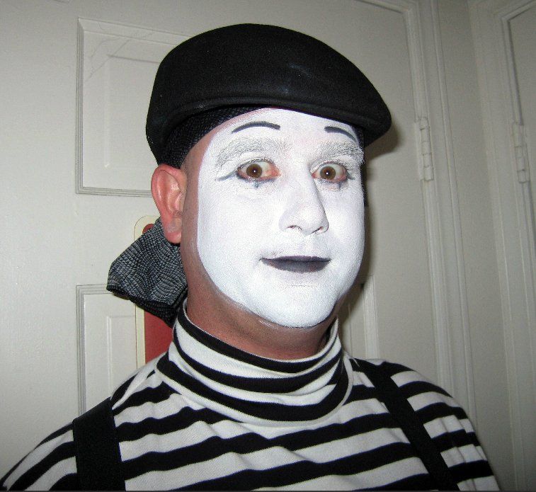 A man with white face paint and a black hat