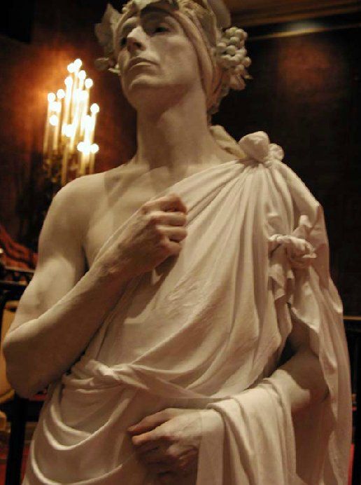 A statue of a man in a white robe with a laurel wreath on his head