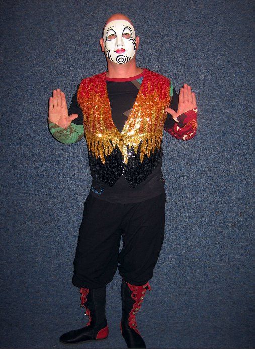 A man in a clown costume is standing with his hands outstretched