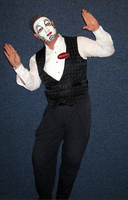 A man wearing a white mask and a black vest is dancing
