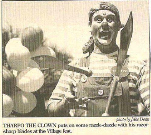 A black and white photo of a clown holding balloons