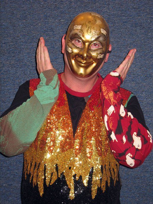 A man wearing a gold mask and a sequined vest