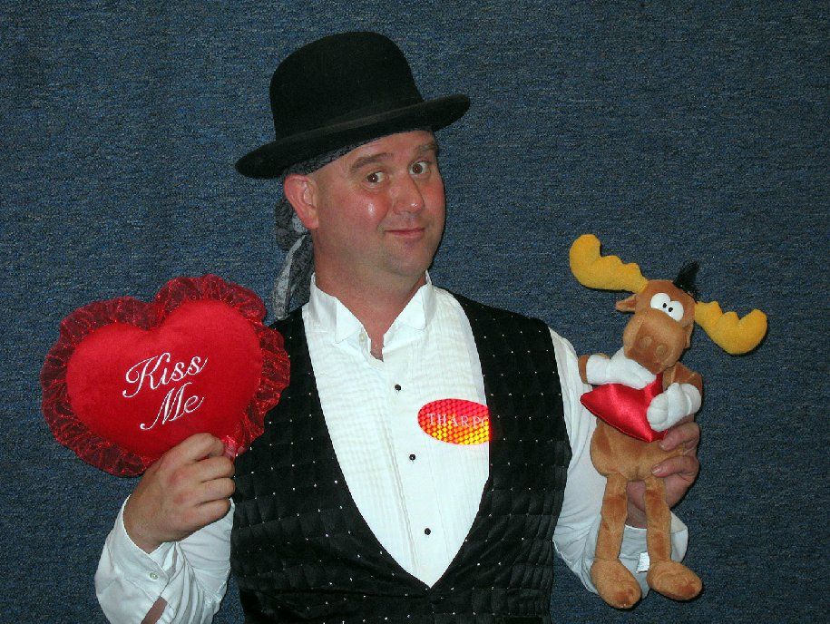 A man holding a stuffed moose and a heart that says kiss me