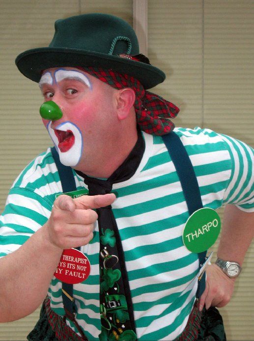 A man dressed as a clown has a tag that says tharpo on it