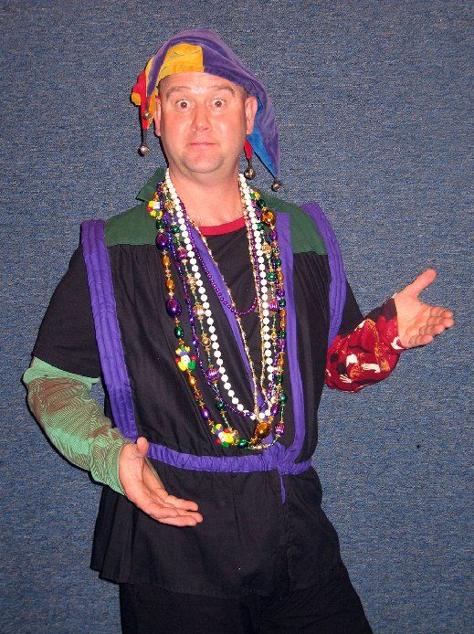 A man wearing a jester hat and a necklace of beads
