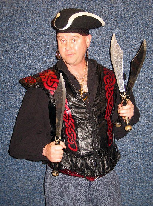 A man in a pirate costume is holding two swords