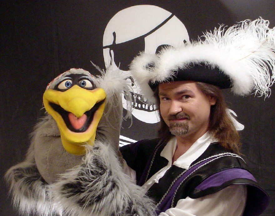 A man in a pirate costume is holding a puppet