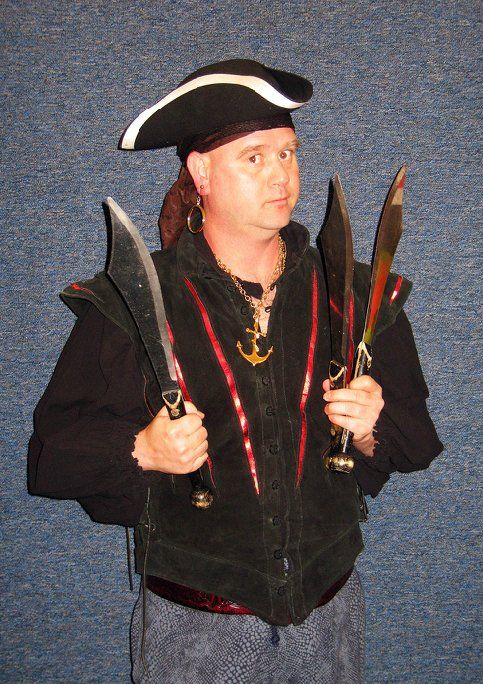 A man in a pirate costume is holding three knives