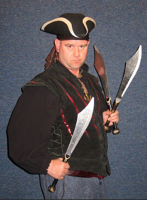 A man in a pirate costume is holding two swords