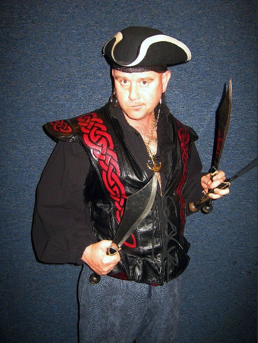 A man in a pirate costume is holding two swords