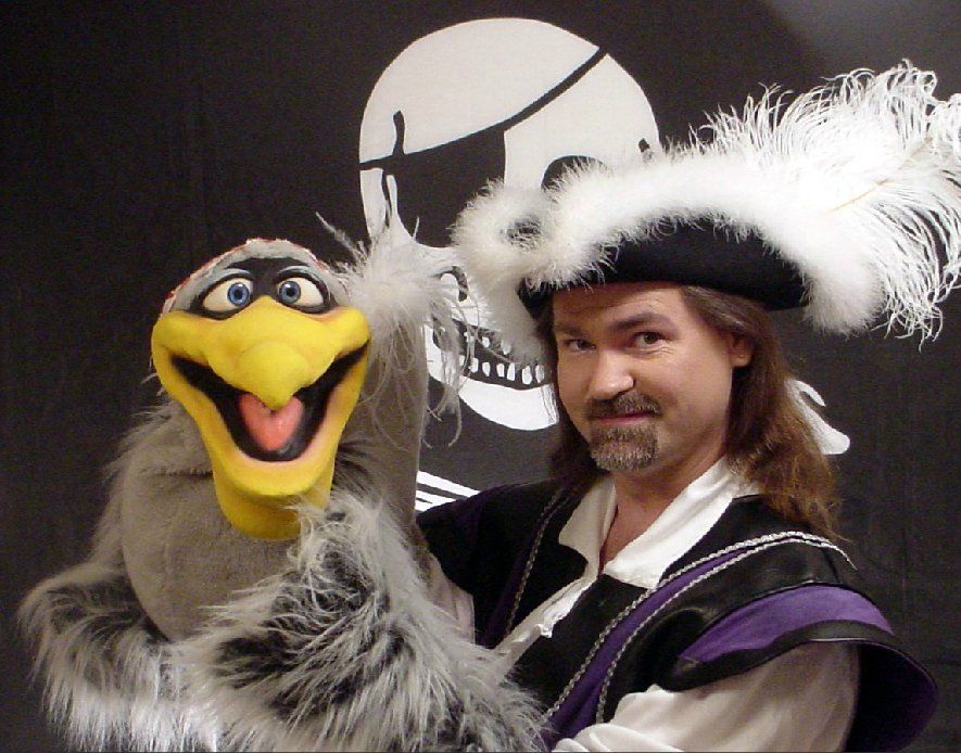 A man in a pirate costume is holding a puppet