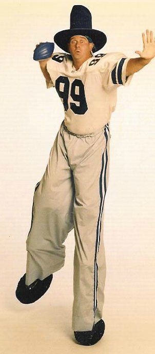 A man wearing a number 99 jersey is standing on stilts