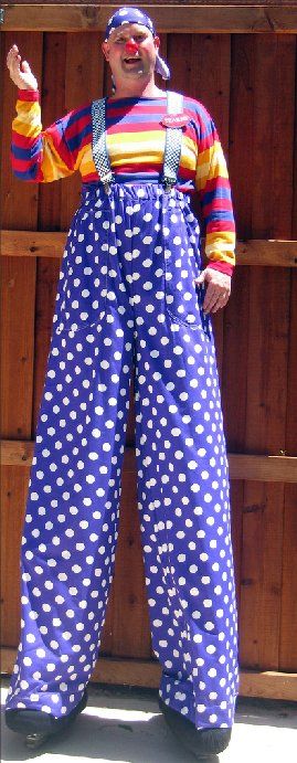 A man in a clown costume is standing on stilts