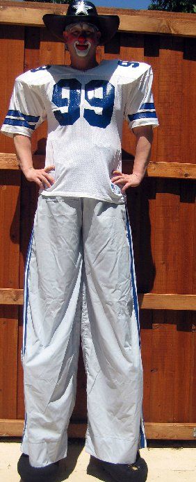 A man on stilts is wearing a football jersey with the number 99 on it