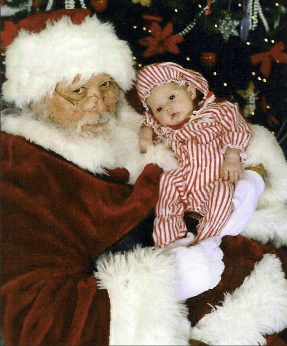 Santa claus is holding a baby in striped pajamas