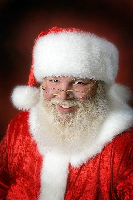 A man with a beard and glasses is dressed as santa claus