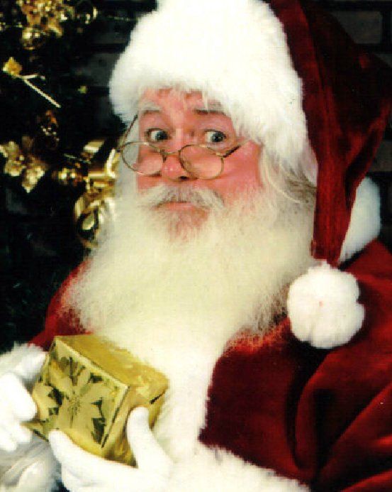 Santa claus is holding a gift in front of a christmas tree