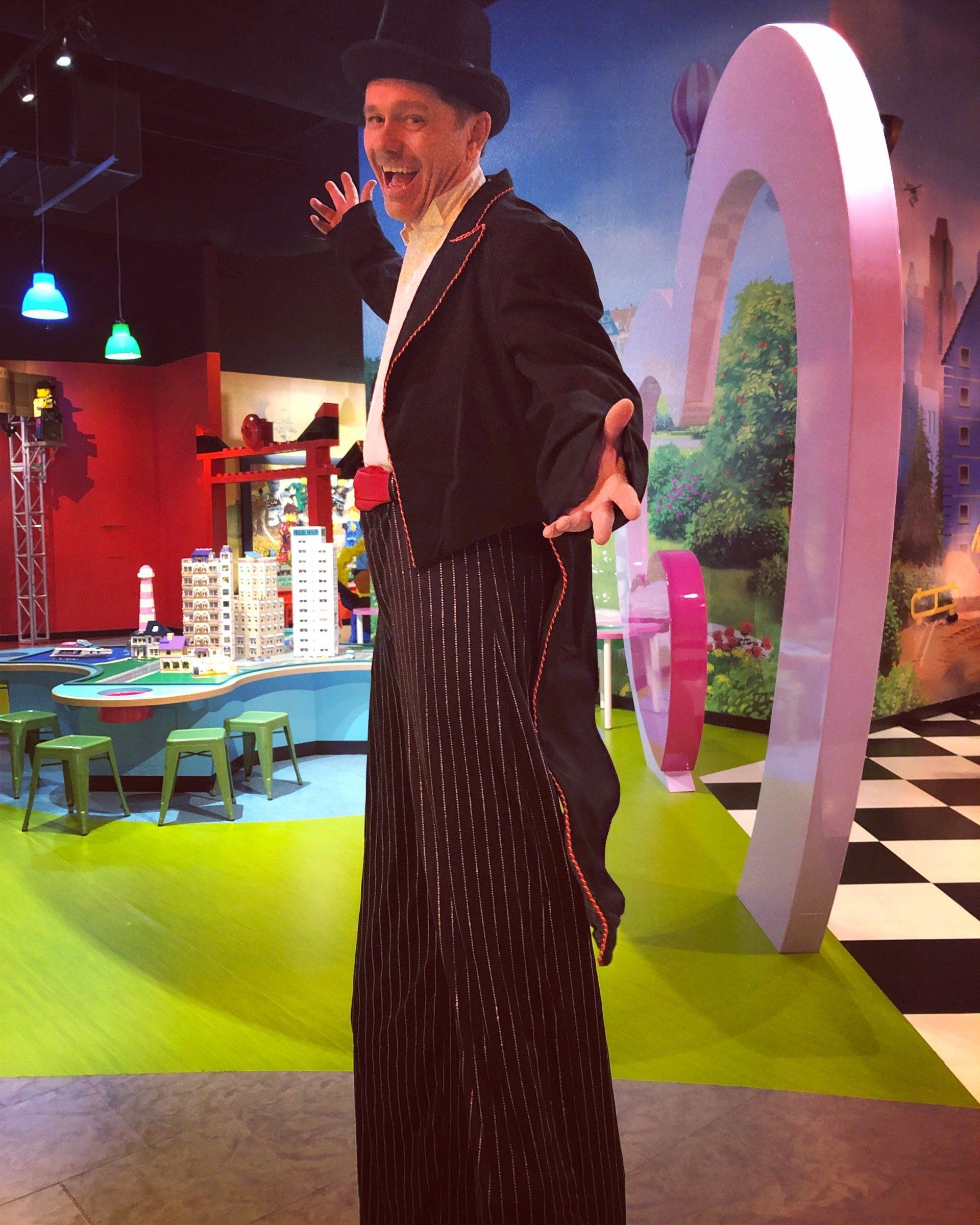 A man in a top hat is standing on stilts
