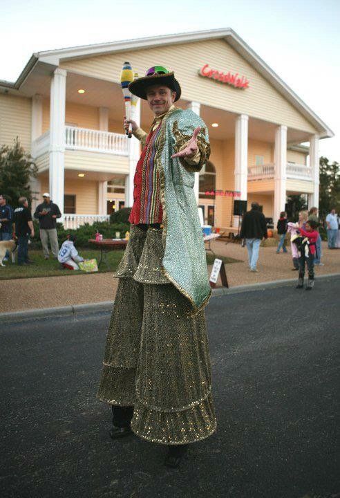 A man on stilts stands in front of a large building that says cinemas