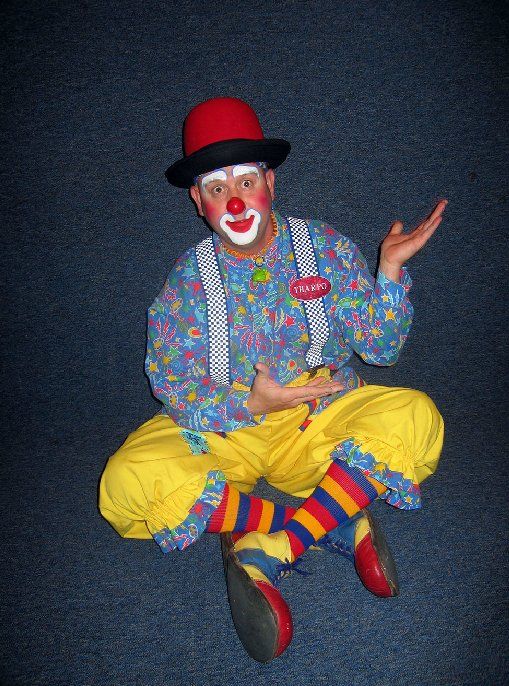 A clown is sitting on the floor with his legs crossed