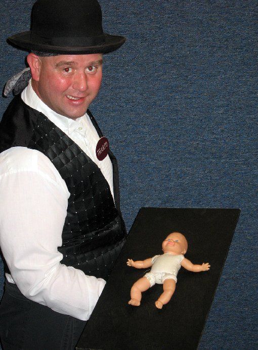 A man in a hat is holding a baby doll
