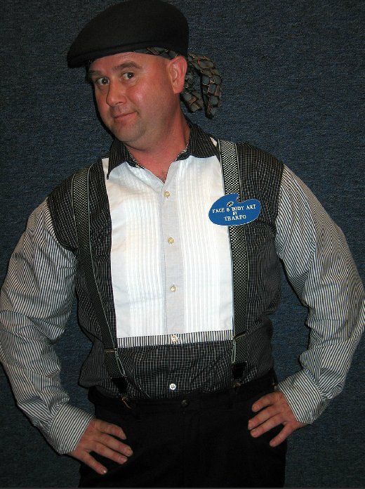 A man wearing suspenders and a hat has a name tag on his chest that says chris