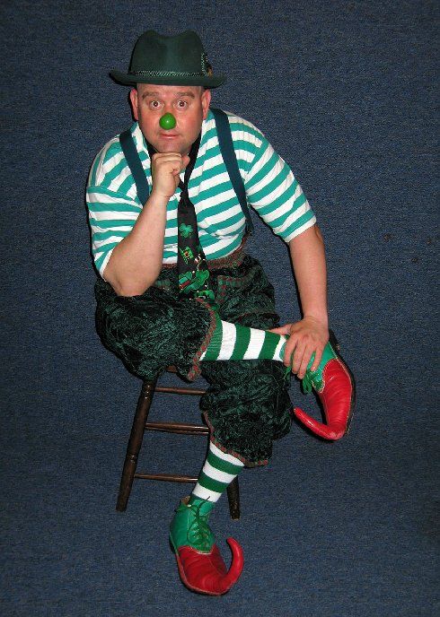 A man dressed as an elf is sitting on a stool