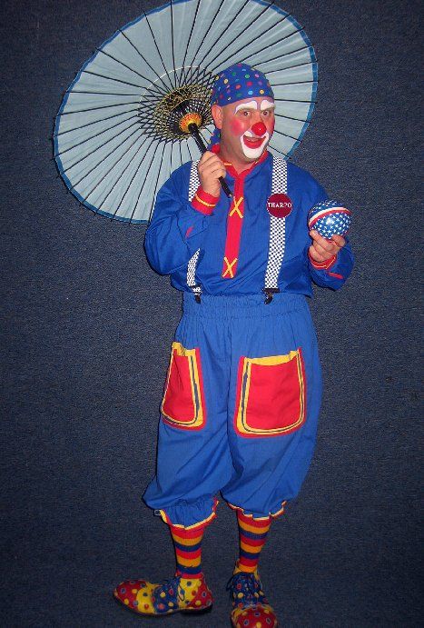 A clown in a blue outfit is holding an umbrella