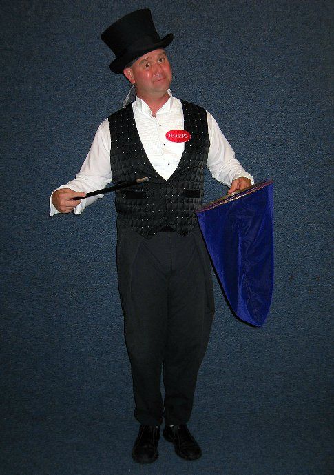 A man in a top hat is holding a wand and a bag