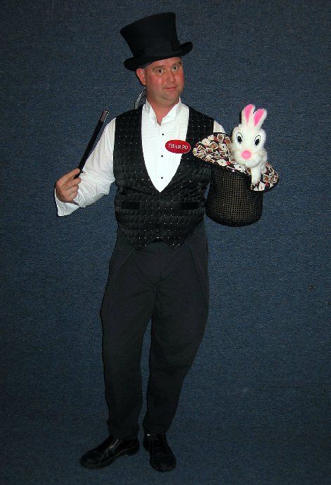 A man in a top hat is holding a rabbit in a basket