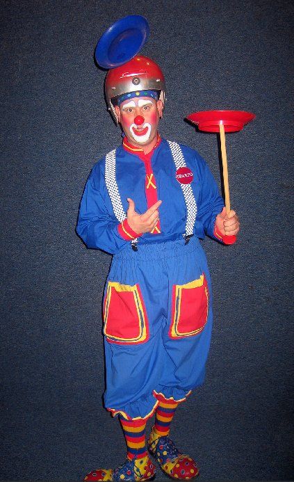 A clown with a plate on his head is holding a plate on a stick