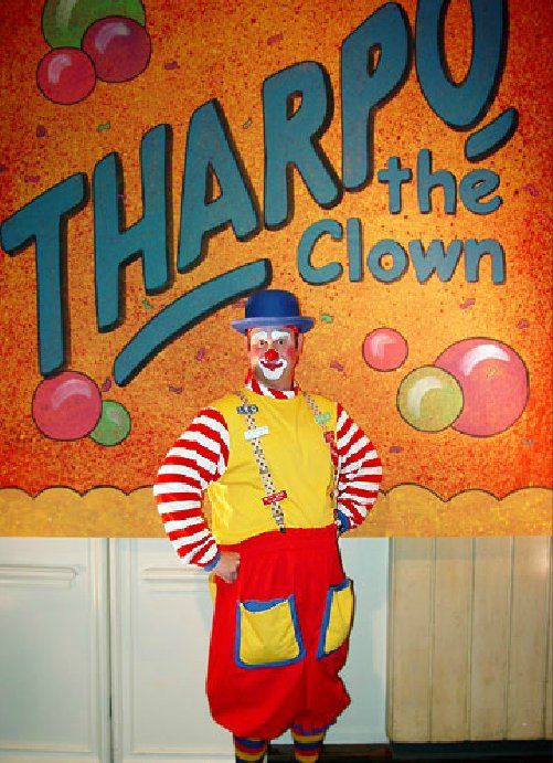 A clown in front of a sign that says tharpo the clown