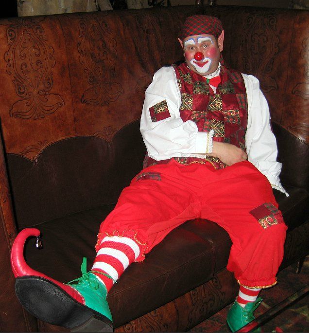 A man dressed as a clown is sitting on a couch