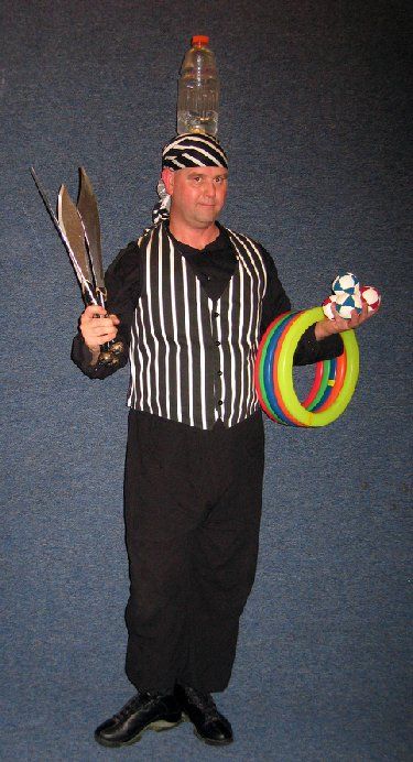 A man in a pirate costume is holding a hula hoop and a bottle on his head