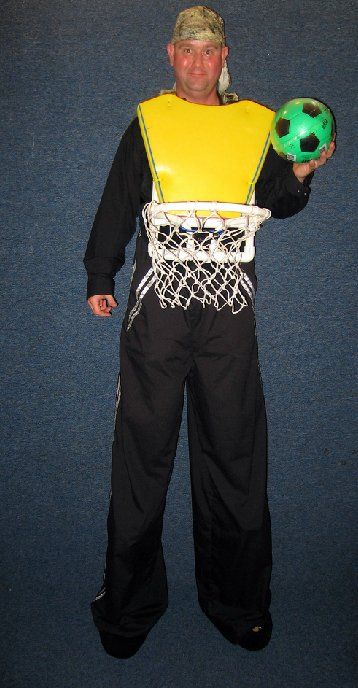 A man in a basketball hoop costume is holding a soccer ball