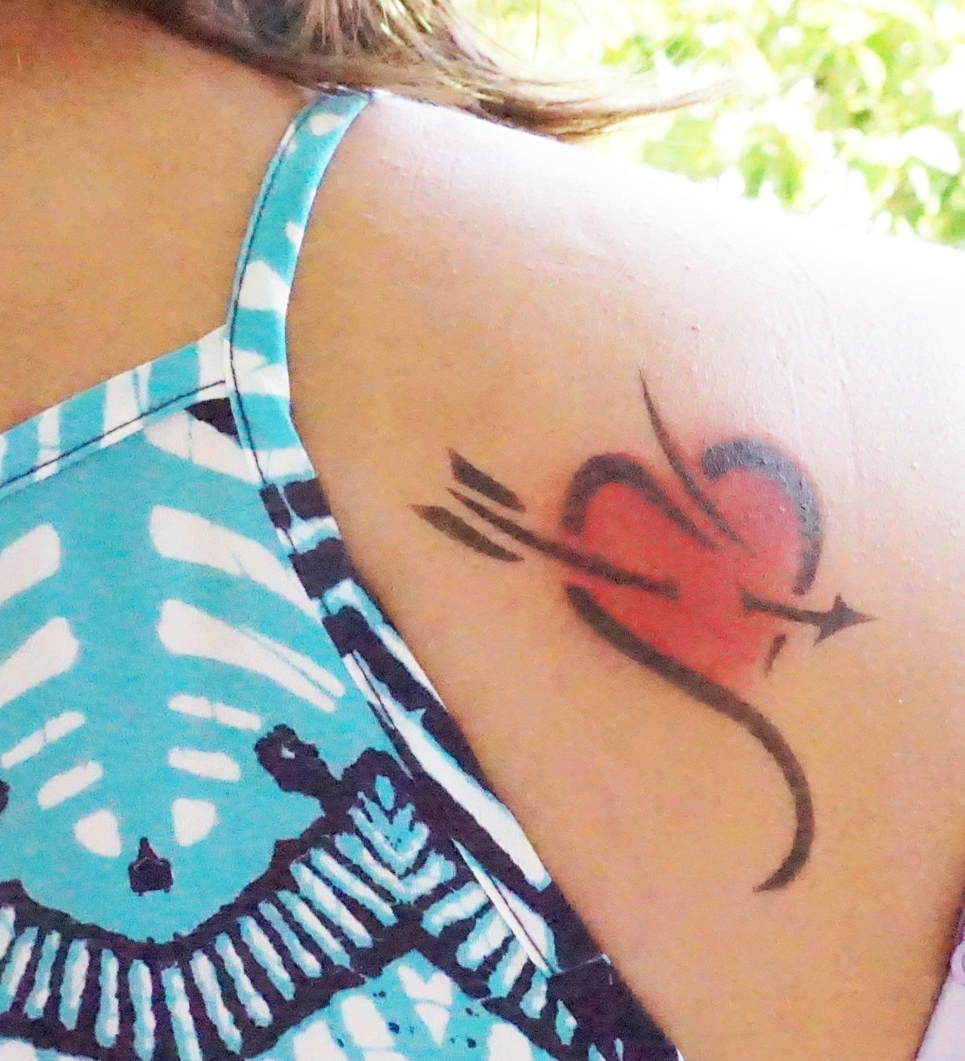 A woman has a tattoo of a heart with an arrow through it
